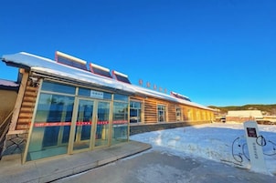 A building with a snow-covered roof, glass doors, and a sign indicating a restaurant or cafe.