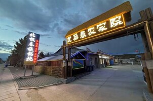 A hotel entrance with a signboard, a small building, and a paved walkway.