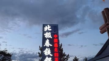 A vertical sign with text against a cloudy sky.