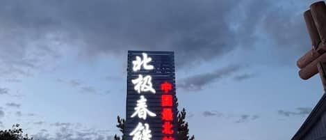 A vertical sign with text against a cloudy sky.