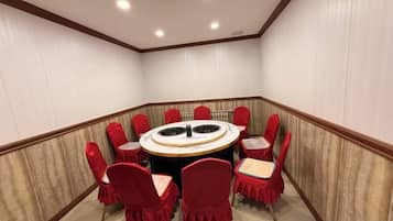 A conference room with a round table and red chairs, white walls, and a wooden floor.