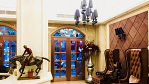 A lobby with a chandelier, a statue of a rider on a horse, a large vase with flowers, and a wall-mounted television. - Gelin Luoman Fengqing Hotel (Lishui)