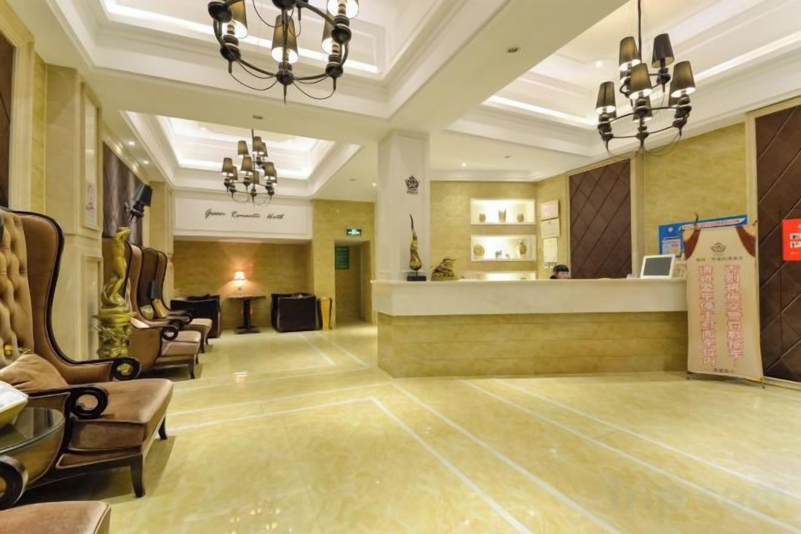Un vestíbulo de hotel con mostrador de recepción, zona de estar y candelabros.