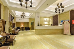 Un vestíbulo de hotel con mostrador de recepción, zona de estar y candelabros.
