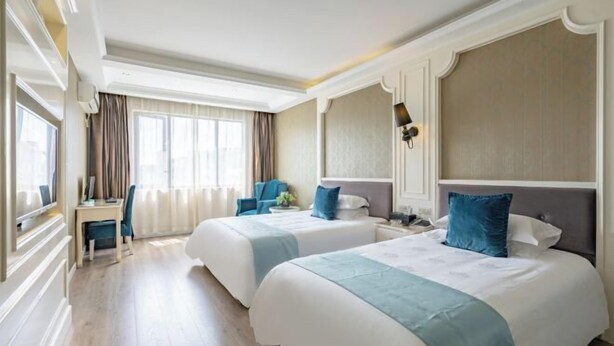 A hotel room with two beds, a desk, and a chair. - Gelin Luoman Fengqing Hotel (Lishui)