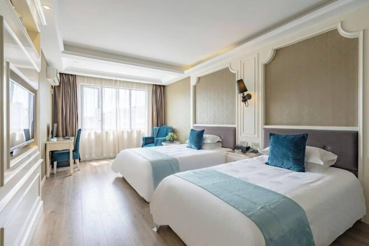 Une chambre d’hôtel avec deux lits, un bureau et une chaise.
