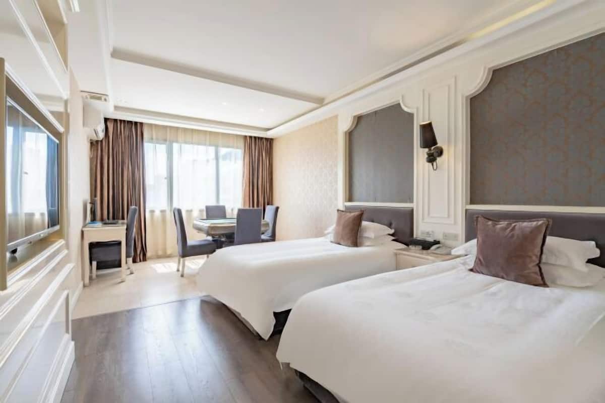 Une chambre d’hôtel avec deux lits, un bureau, une chaise et un téléviseur.