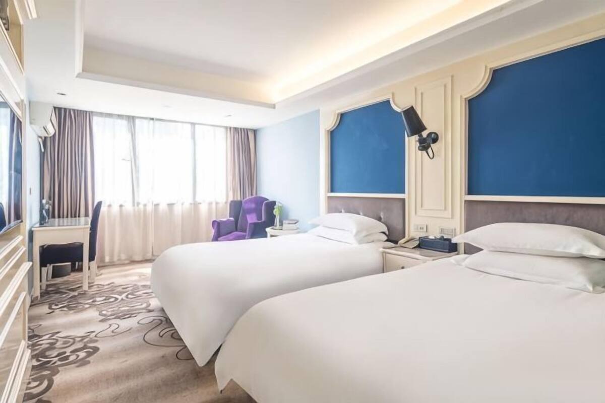 Une chambre d’hôtel avec deux lits, un bureau, une chaise et un téléviseur.
