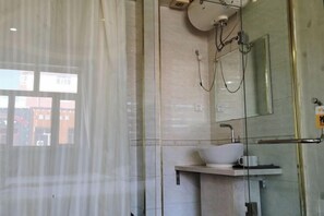 Une salle de bain moderne avec une douche à parois de verre, un lavabo blanc avec un porte-savon et un miroir au-dessus du lavabo.