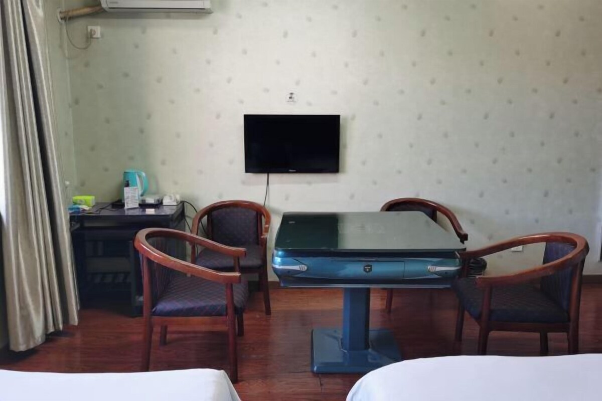 Une chambre d’hôtel avec un lit, un bureau équipé d’un ordinateur, un téléviseur fixé au mur et deux chaises disposées autour d’une table.