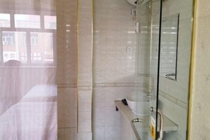Une salle de bain avec une douche à parois de verre, un lavabo blanc et un miroir.