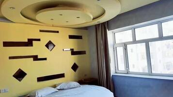 Ein Schlafzimmer mit einem Bett, einem Fenster und einer Wand mit geometrischen Mustern.