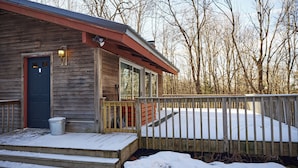 A wooden cabin with a blue door, a small porch, and a wooden deck.