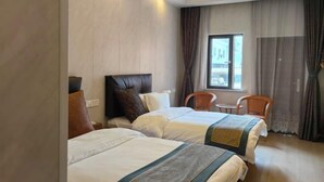 Ein Hotelzimmer mit zwei Betten, einem kleinen Tisch und einem Stuhl.