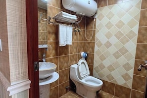 Casa de banho com sanita, lavatório, porta-toalhas e chuveiro.
