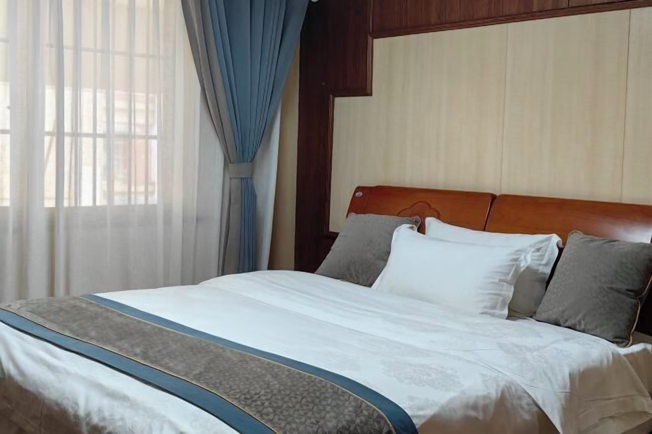 Un lit bien fait, avec une tête de lit en bois, une literie blanche et une bande décorative bleue.