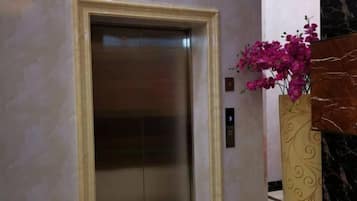 An elevator with a marble wall and a decorative vase with flowers.