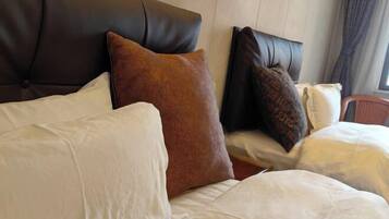 A bed with white and brown pillows, a dark headboard, and a window with curtains.