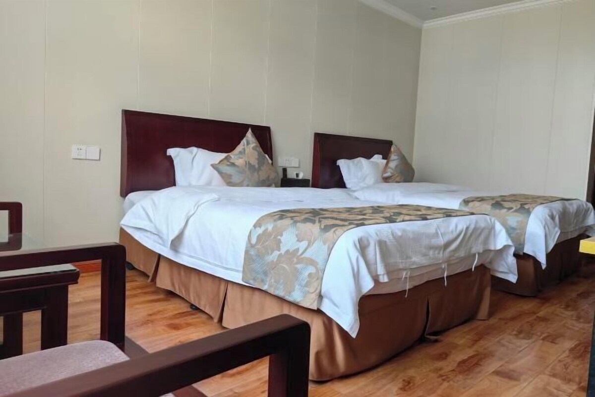 Habitación de hotel con dos camas, cabeceros de madera y suelo de madera.