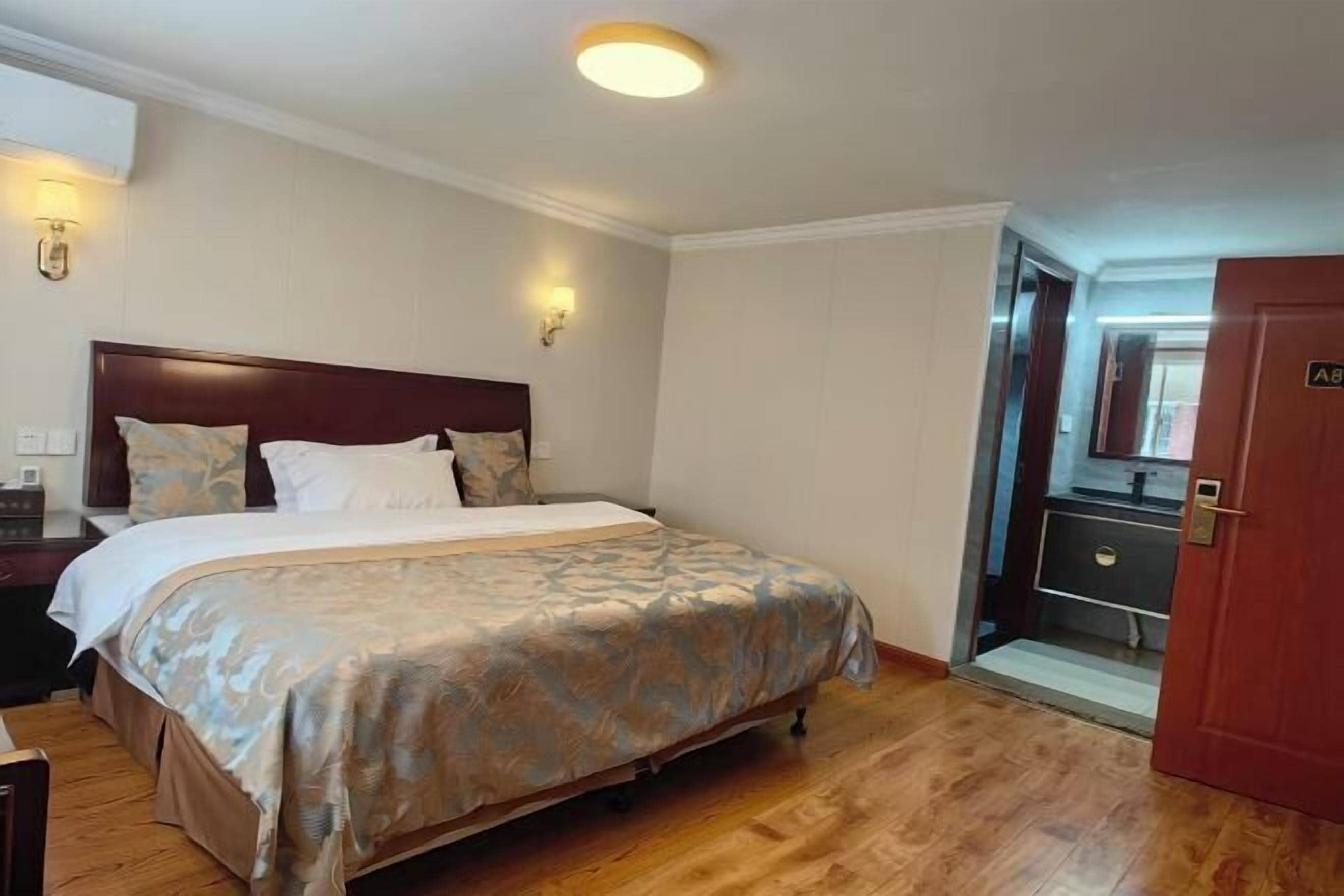Une chambre d’hôtel avec un lit, une table de chevet, une lampe et une porte avec une pancarte.