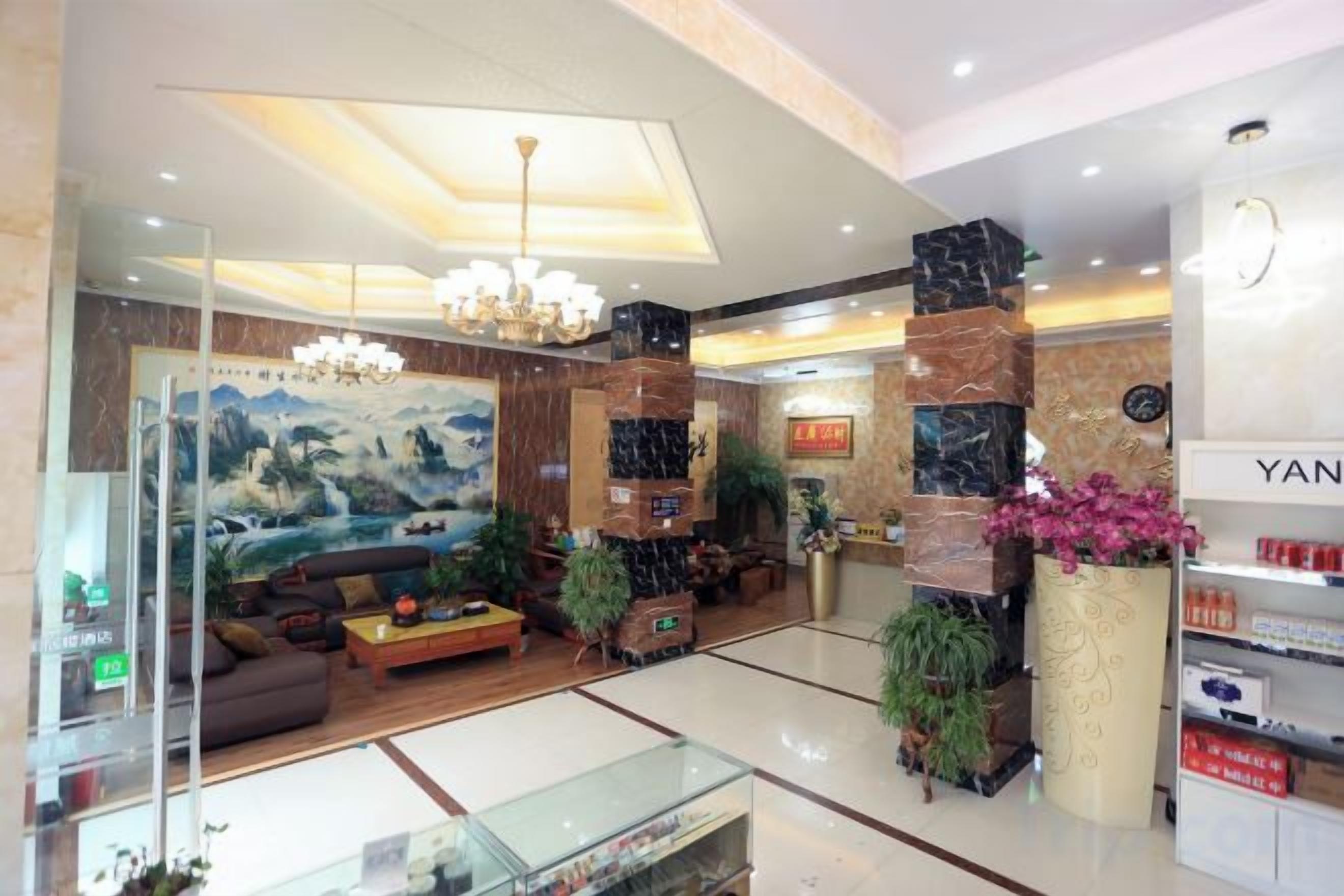 A hotel lobby with a reception desk, seating area, and a large painting on the wall.