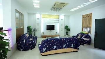 A modern living room with a flat-screen TV, two bean bag chairs, a coffee table, and a large mirror.