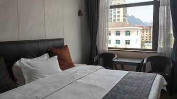 A hotel room with a bed, a small table, and a chair.