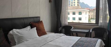 A hotel room with a bed, a small table, and a chair.