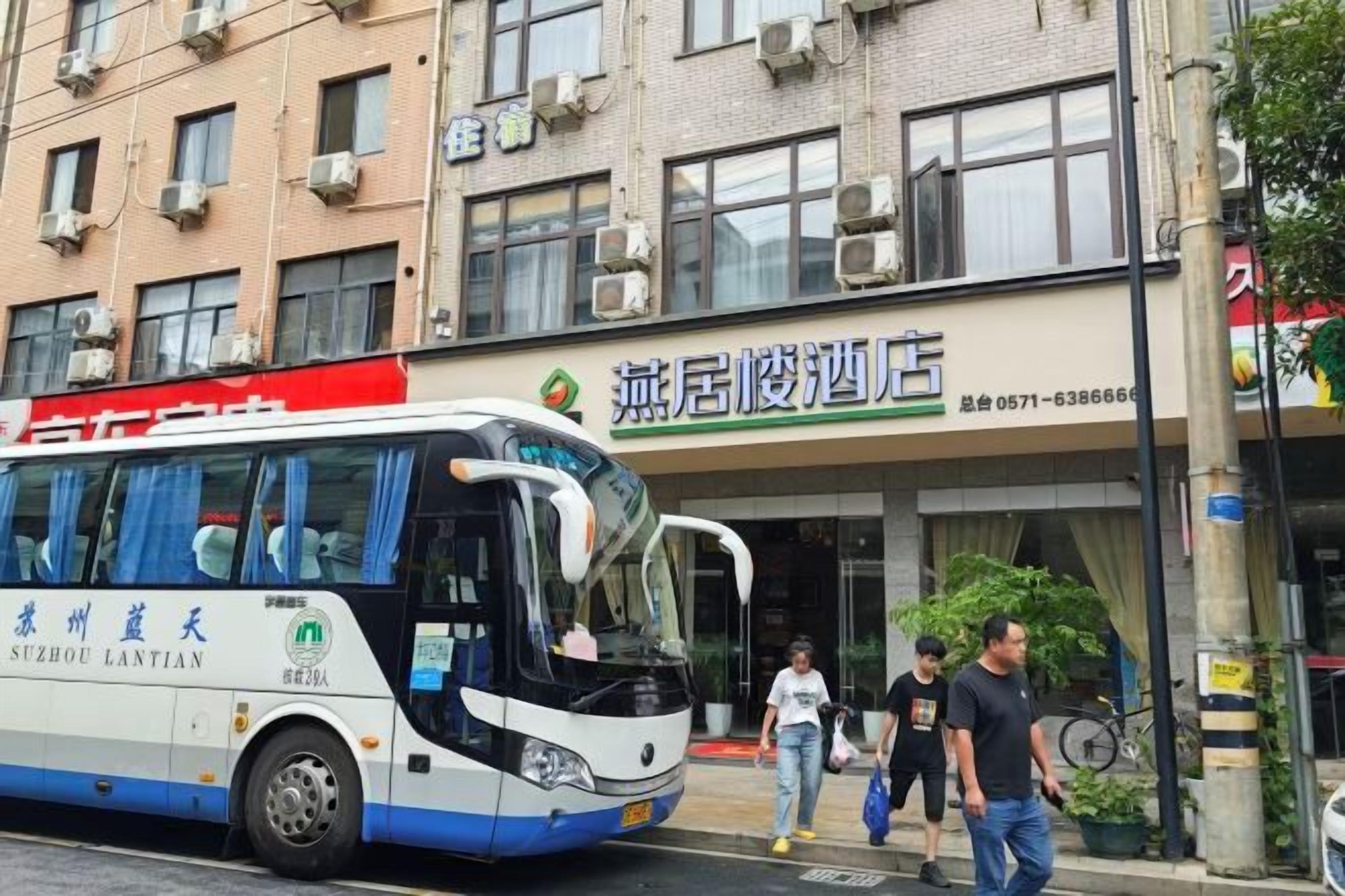 Un autobús estacionado frente a un edificio con un letrero que dice 'Zhangjiu Mansion Hotel'.
