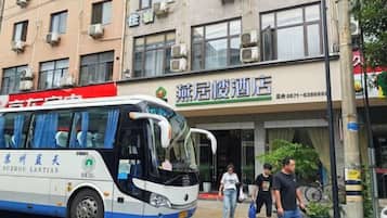 Un autobús estacionado frente a un edificio con un letrero que dice 'Zhangjiu Mansion Hotel'.