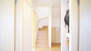 A hallway leading to a staircase with a wooden handrail. - DUO ‧ OKINAWA (Onna)