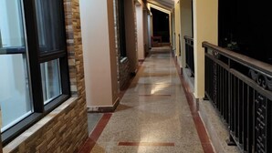 A corridor with a stone wall on one side and a balcony railing on the other.