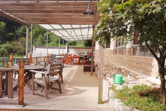 Un patio al aire libre con mobiliario de madera, un pérgola y vistas a un paisaje natural.