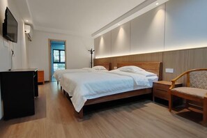 A modern hotel room with a large bed, a desk, and a TV.