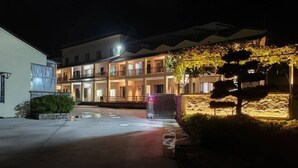 A multi-story hotel with a covered outdoor area, a security gate, and a well-lit entrance.
