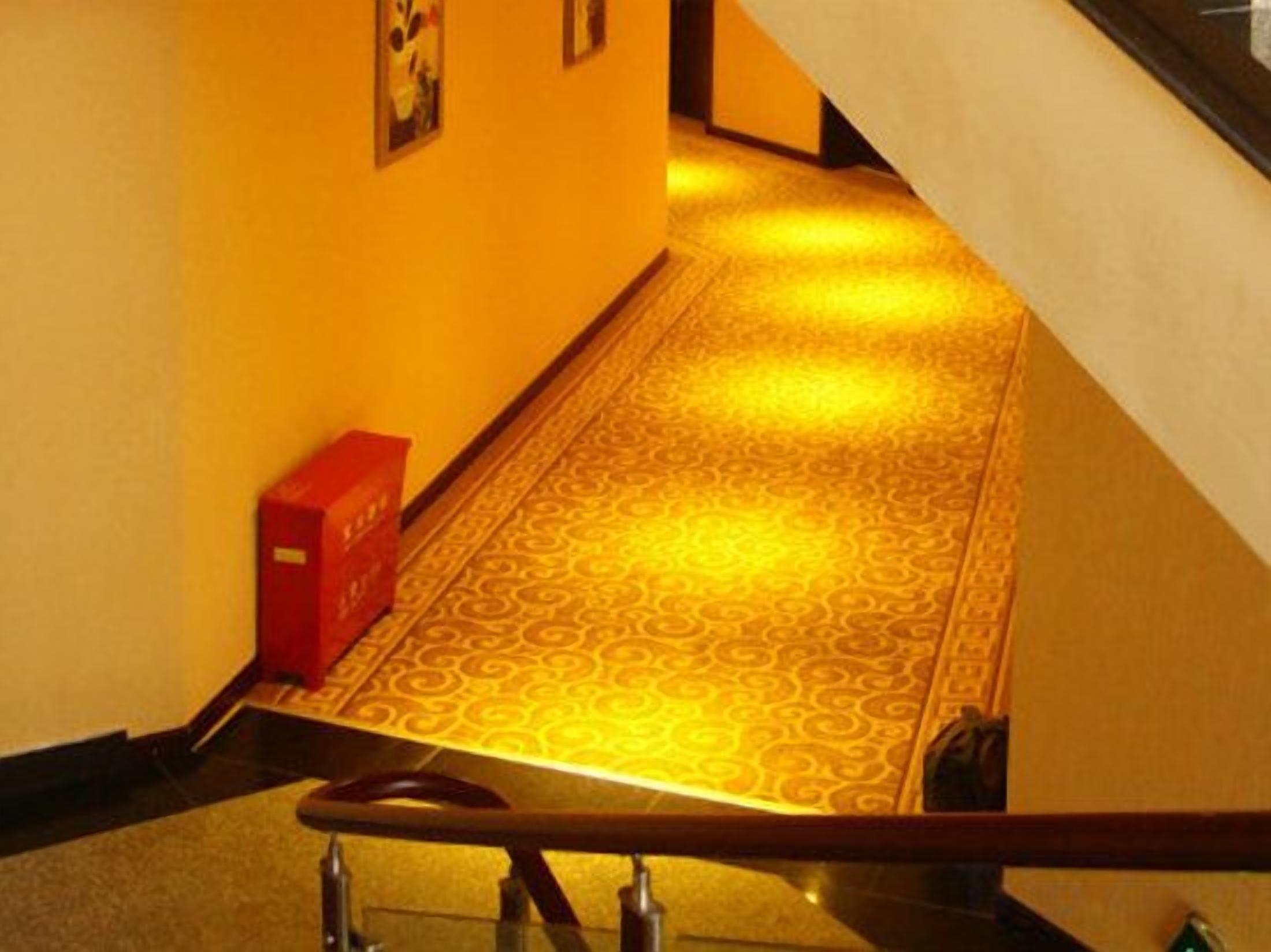 A hallway with patterned flooring, a red object on the left, and a staircase on the right.