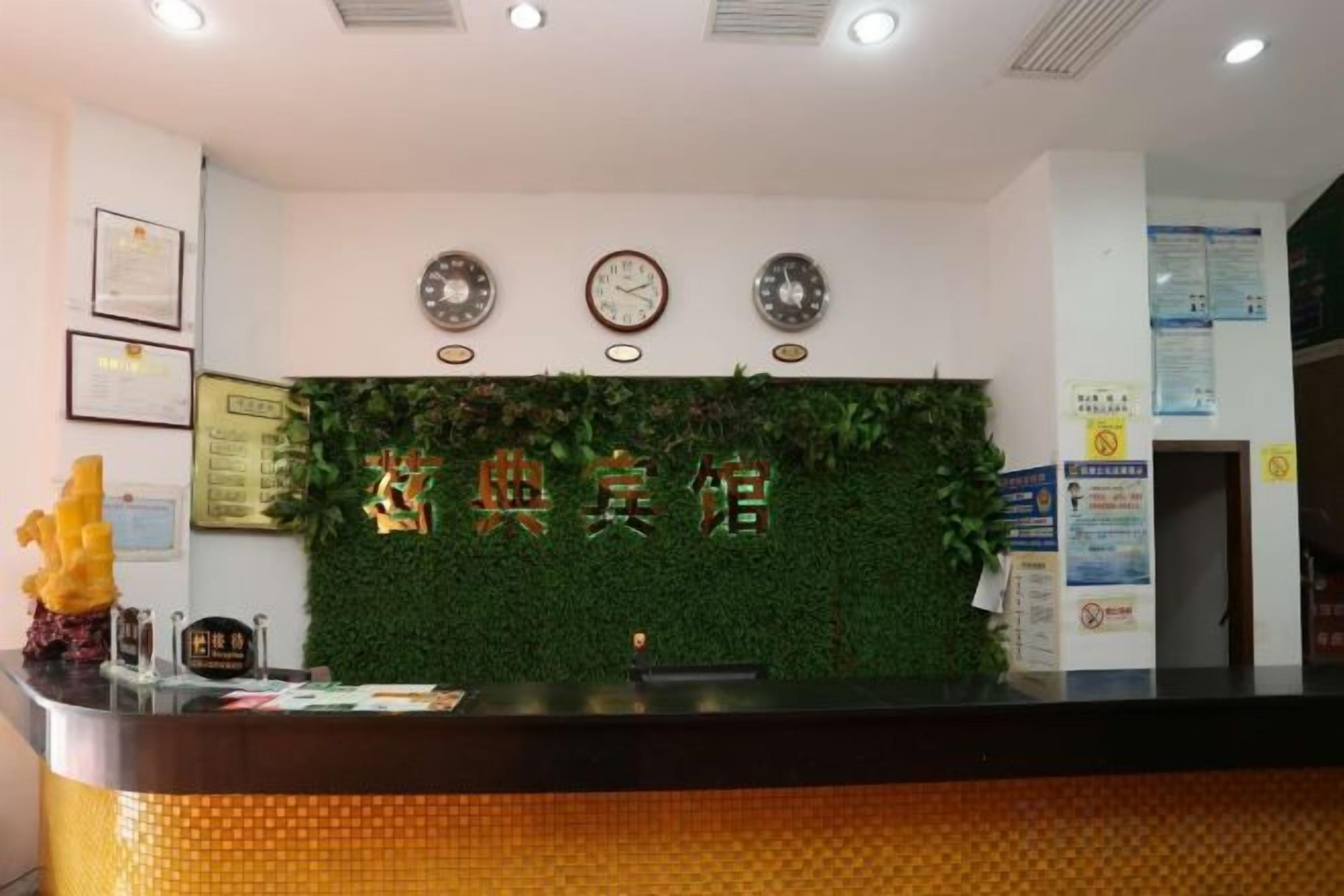 A reception desk with a green wall, clocks, and framed certificates.