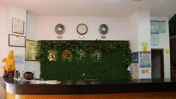 A reception desk with a green wall, clocks, and framed certificates.