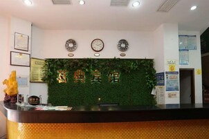 Un mostrador de recepción con una pared verde, relojes y diplomas enmarcados.