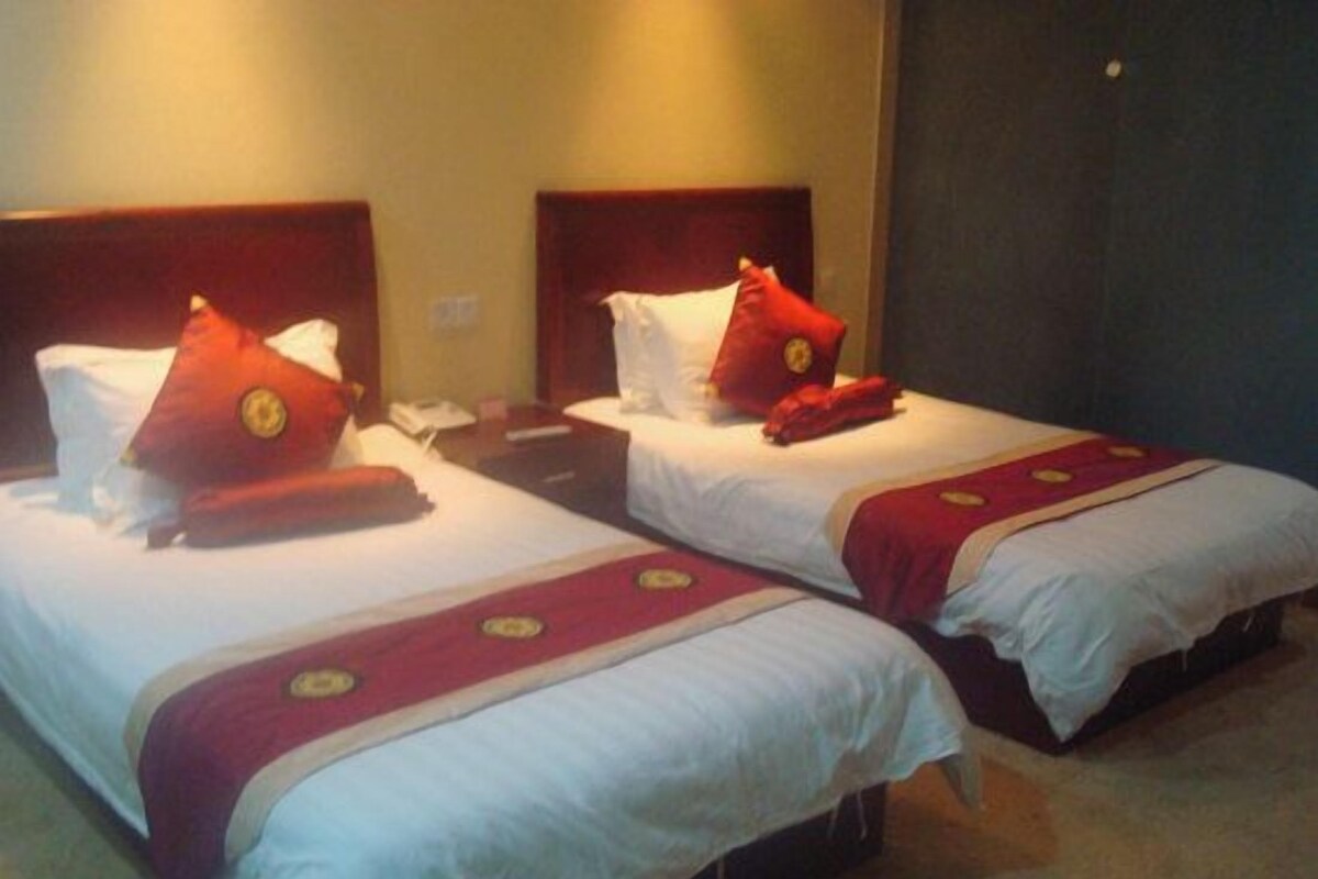 Two single beds with wooden headboards, white bedding, and red pillows with a circular emblem.