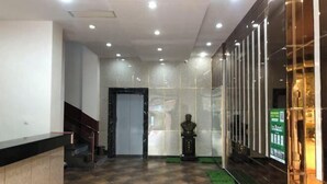 A lobby with a reception desk, a staircase, a statue, and a glass wall with vertical lines. - Ming Dian Hotel (Shaoshan)