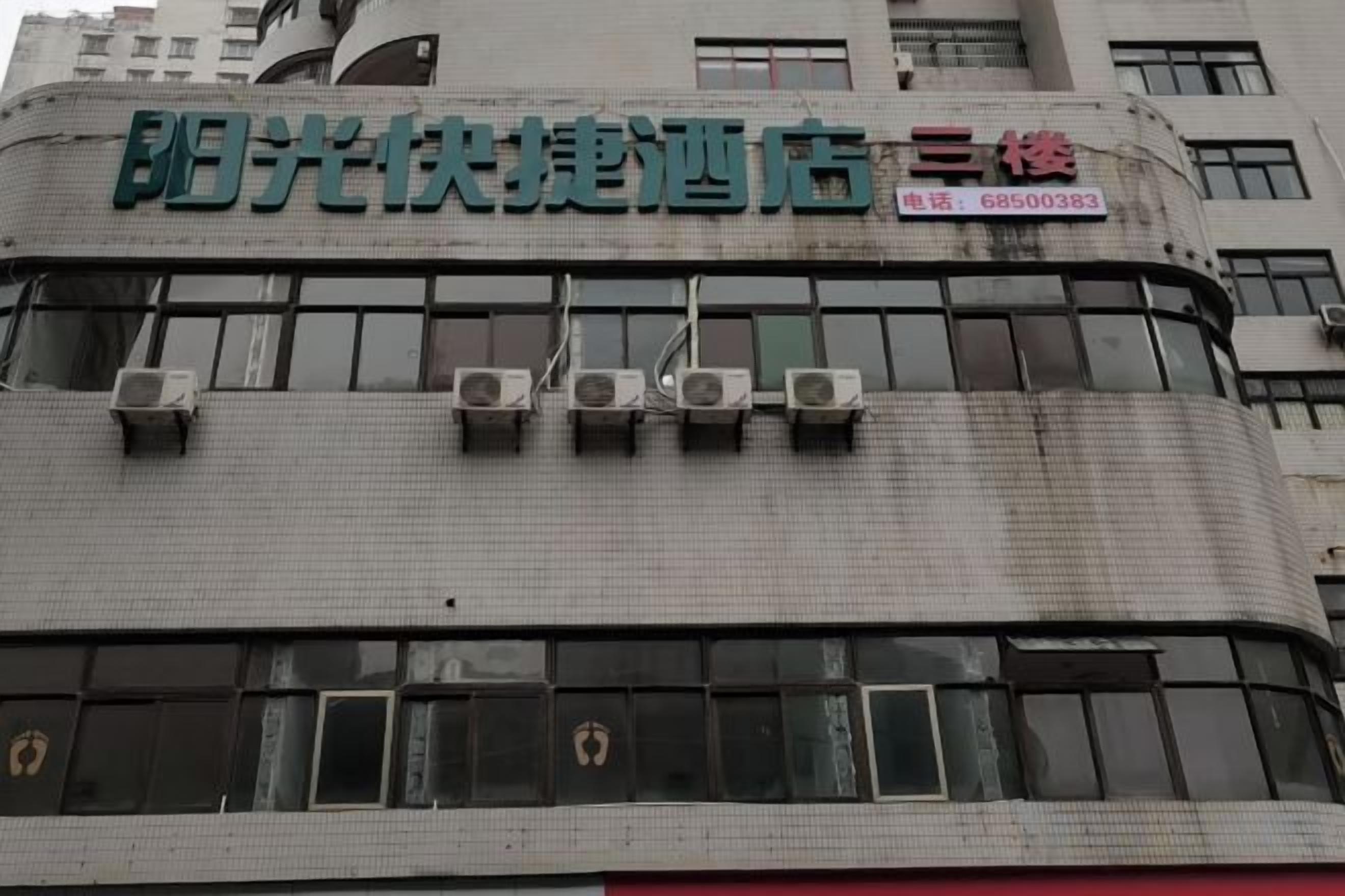 Un edificio con un letrero que dice '阳光快捷酒店' y un número de teléfono '68500383'.