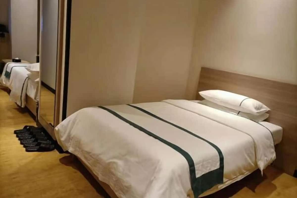 A hotel room with a single bed, a wooden headboard, and a mirror.