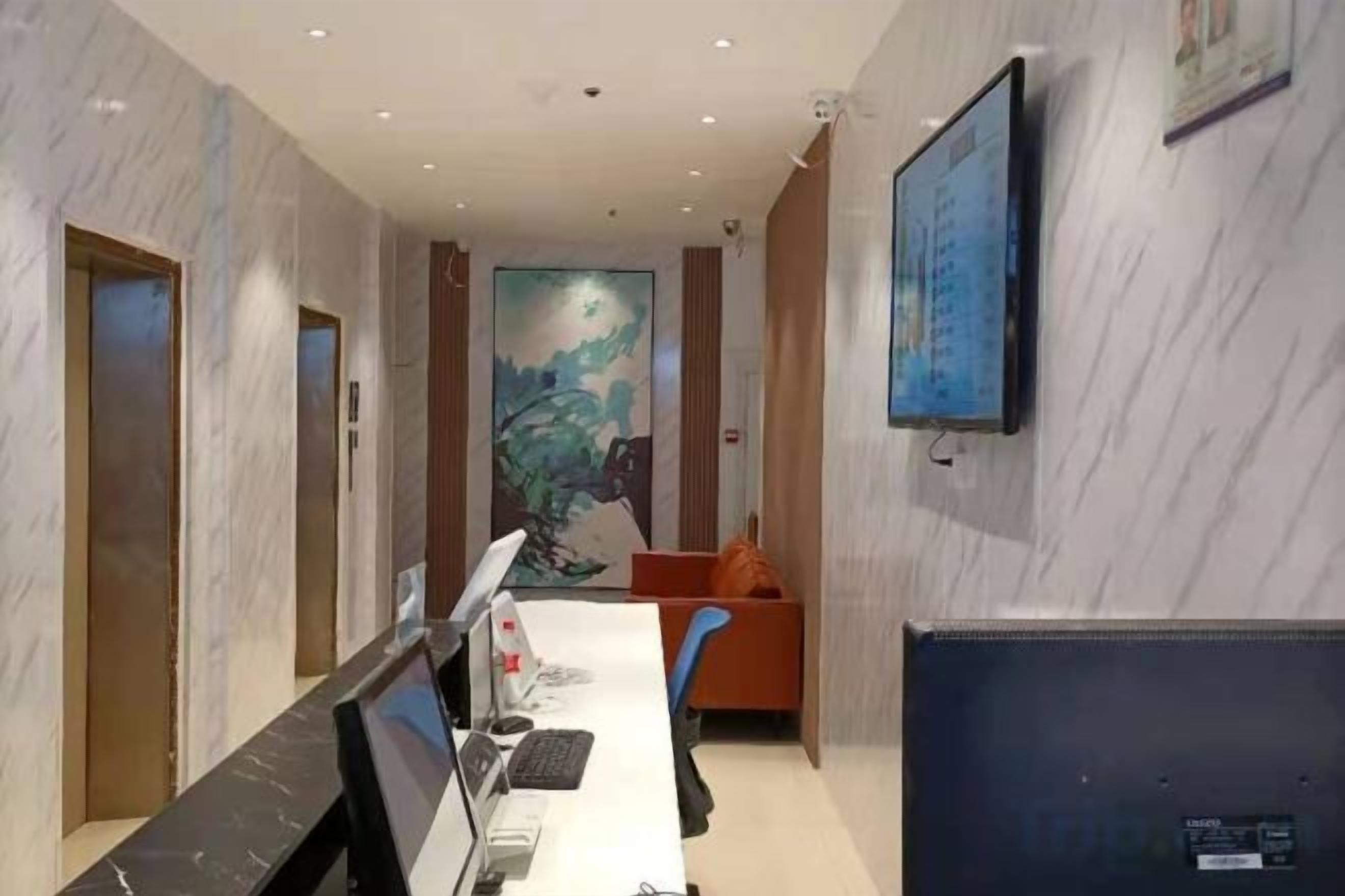 A hotel conference room with a long table, chairs, a TV, and a painting on the wall.