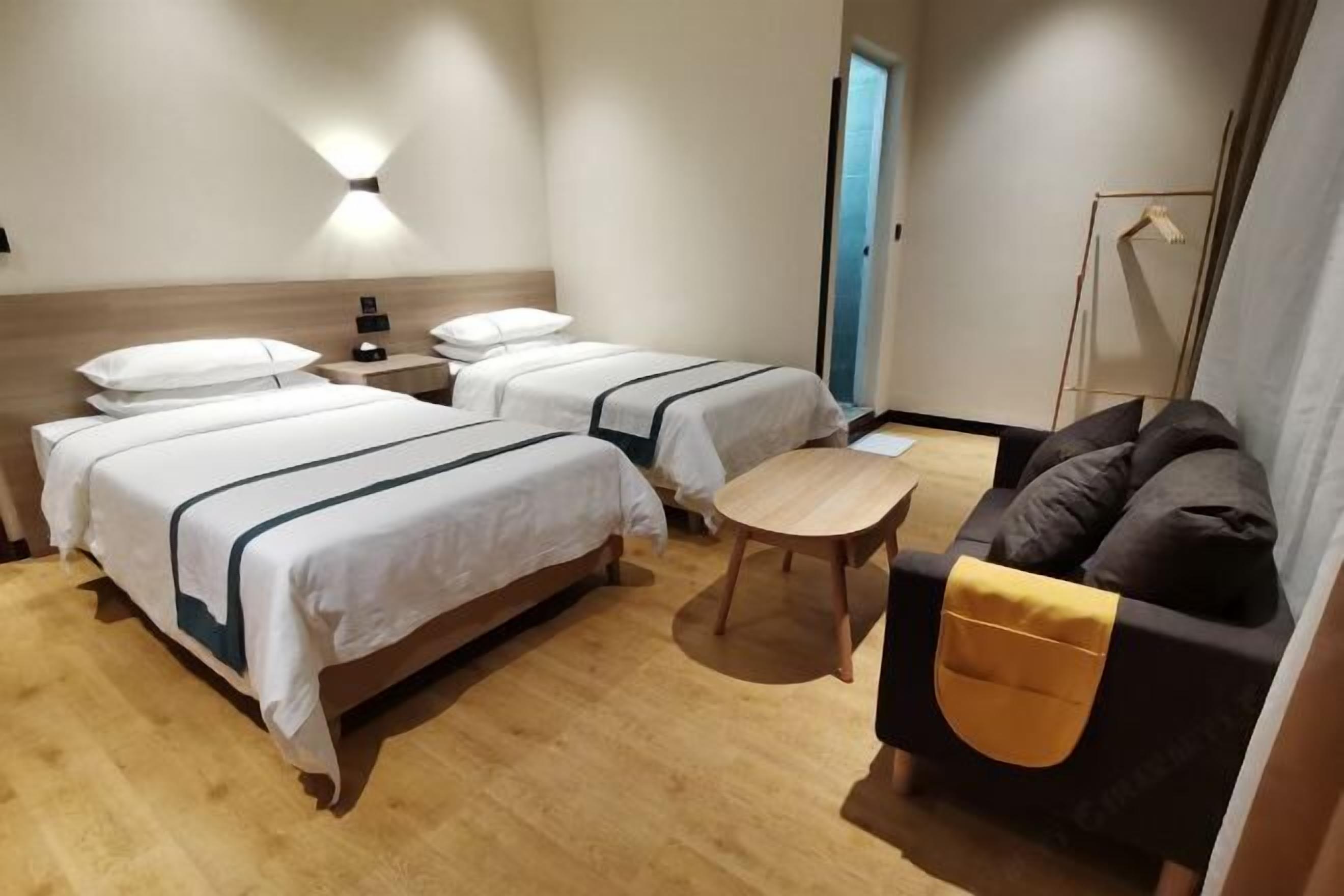 A hotel room with two beds, a sofa, a small table, and a wardrobe.