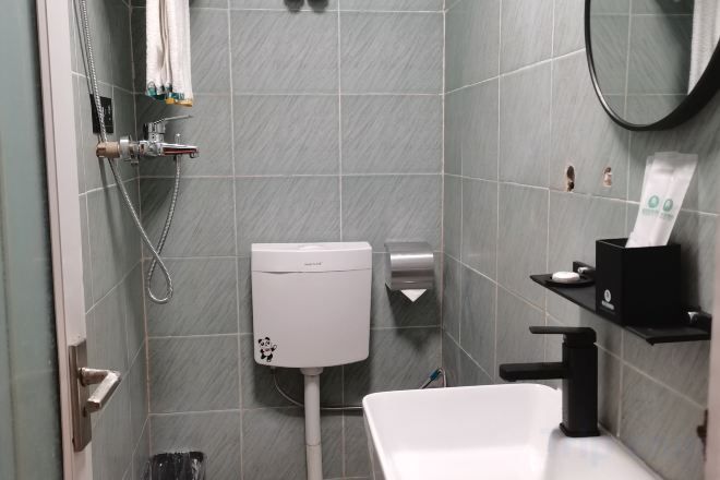 A bathroom with a toilet, sink, and shower area.
