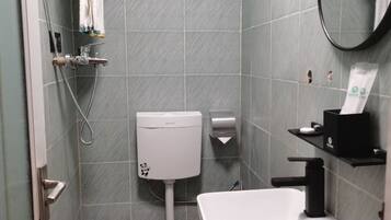A bathroom with a toilet, sink, and shower area.