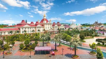 A large, ornate building with multiple domes and a central tower, surrounded by well-manicured gardens and palm trees.