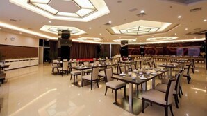 A spacious dining area with multiple tables and chairs, high ceiling with geometric light fixtures, and a polished floor. - Fangte Dongxiang Hotel (Zhuzhou)