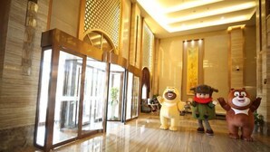 A lobby with a glass entrance, a decorative wall, and two bear statues. - Fangte Dongxiang Hotel (Zhuzhou)